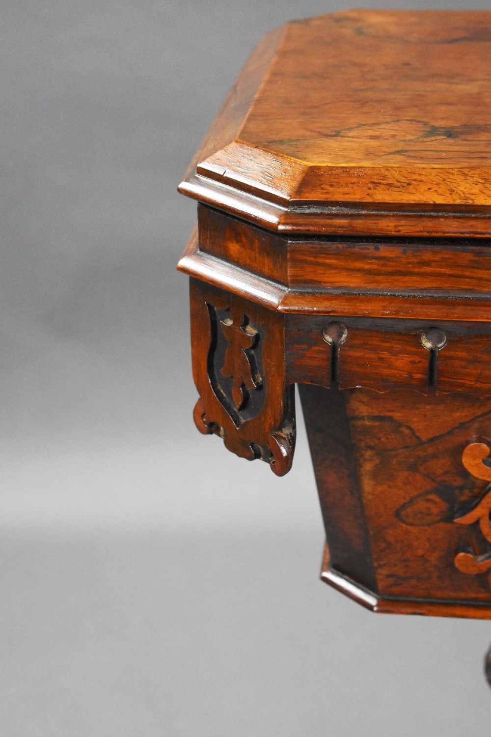 A William IV rosewood tea poy featuring a hinged lidded box top, carved openwork scrolls, a turned pedestal column, and a four-point base with scroll feet. View XIV