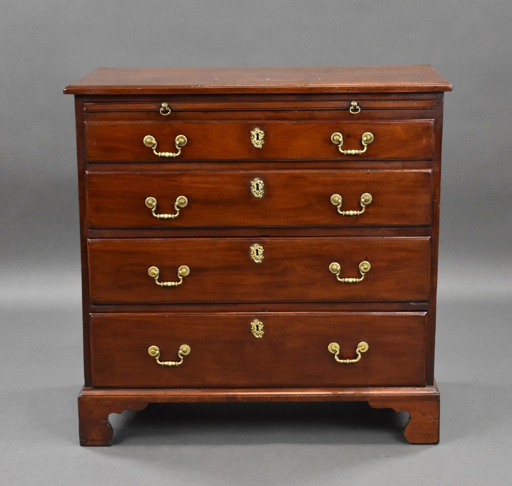 A George III mahogany bachelors chest of drawers featuring four graduated drawers, a pull-out brushing slide, brass swan-neck handles, and bracket feet. View II