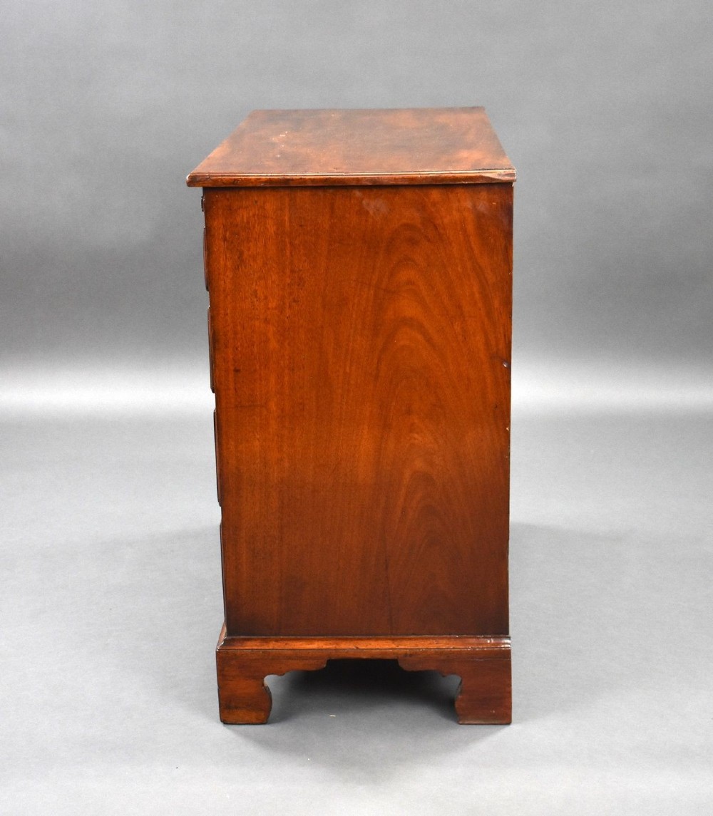 A George III mahogany bachelors chest of drawers featuring four graduated drawers, a pull-out brushing slide, brass swan-neck handles, and bracket feet. View IV