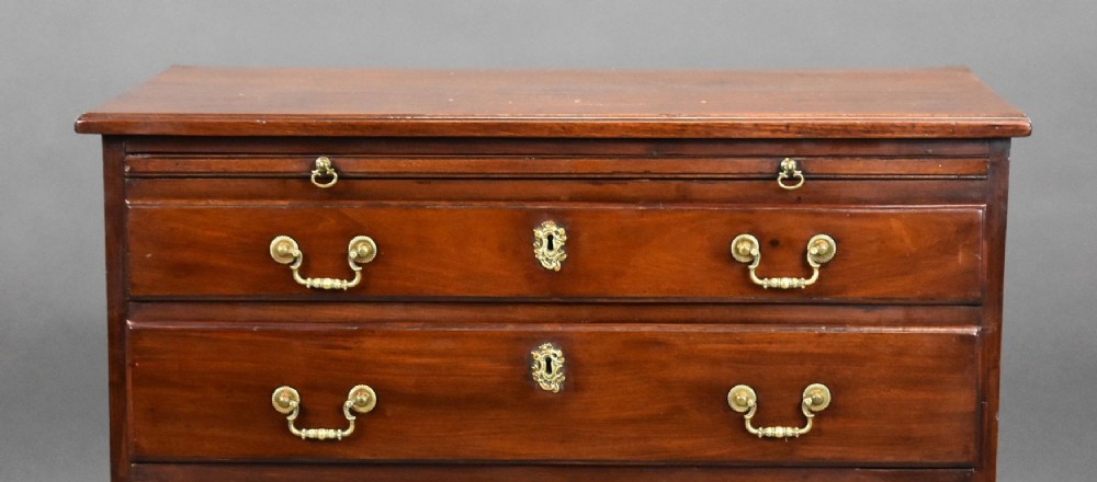 A George III mahogany bachelors chest of drawers featuring four graduated drawers, a pull-out brushing slide, brass swan-neck handles, and bracket feet. View VI