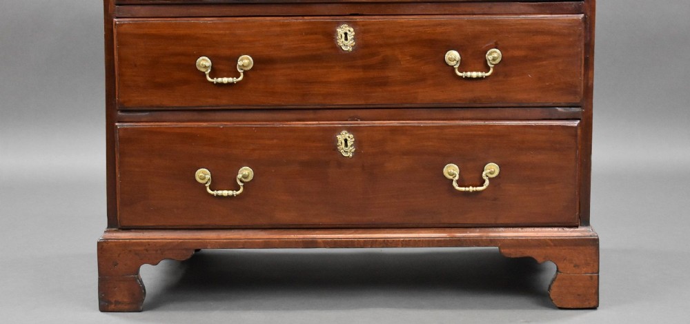 A George III mahogany bachelors chest of drawers featuring four graduated drawers, a pull-out brushing slide, brass swan-neck handles, and bracket feet. View VII