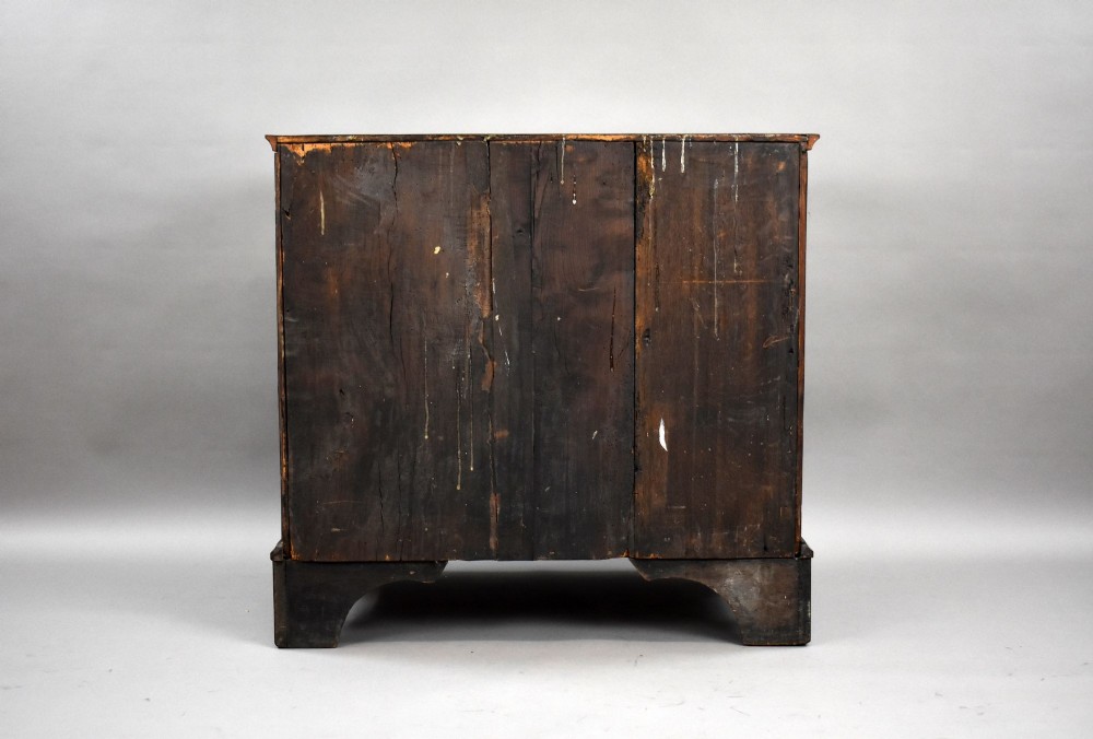A Georgian burr walnut chest of drawers featuring two short over two long drawers with brass drop handles and pierced escutcheons, supported by bracket feet. View VII
