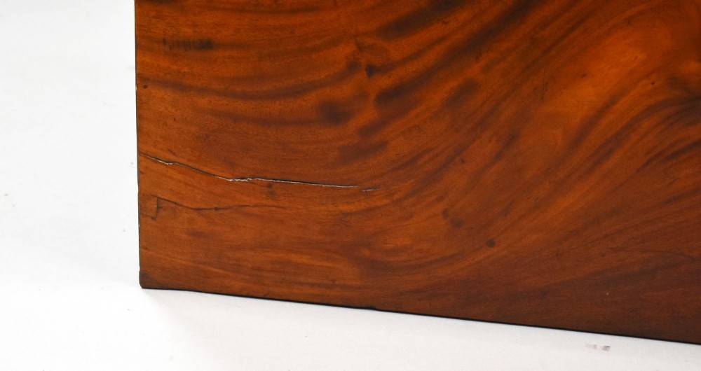 A Regency mahogany chest of drawers featuring three full-length drawers with brass knobs, bone keyhole escutcheons, flame veneer fronts, and a shaped apron base. View VII