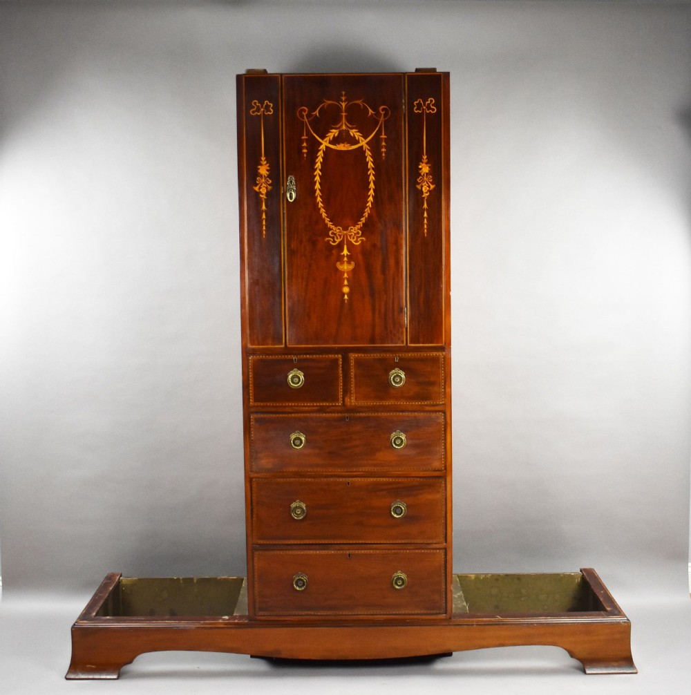 An Edwardian mahogany triple wardrobe featuring twin full-length mirror doors flanking a central inlaid cupboard and four drawers. View II