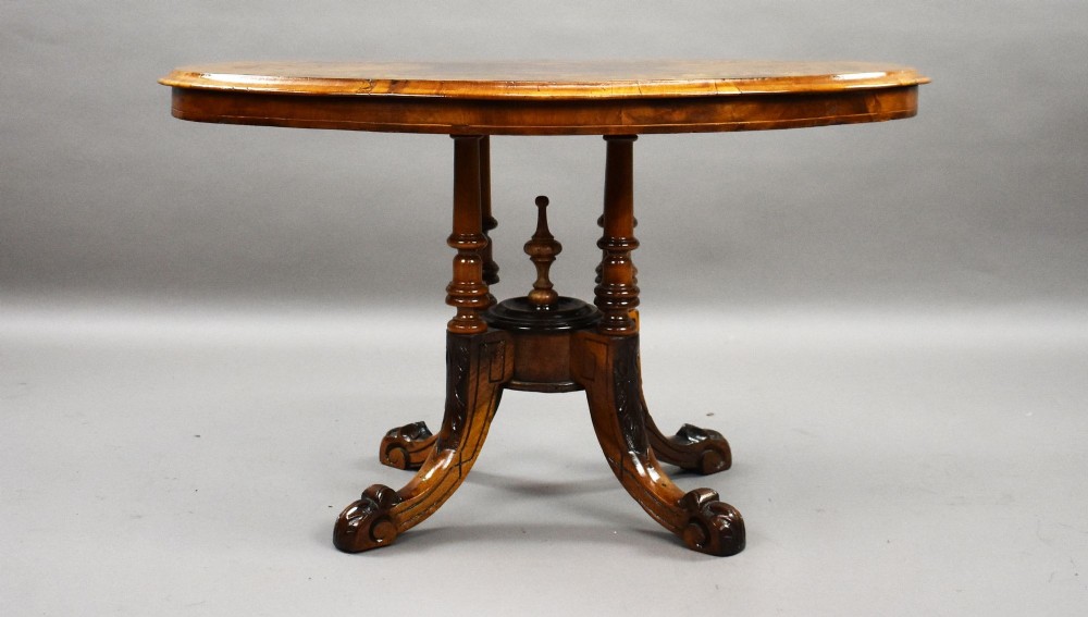 An oval Victorian burr walnut coffee table with floral marquetry inlay, four turned columns, and carved splayed feet. View III