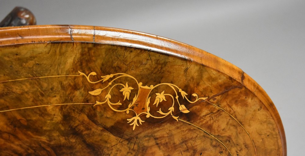 An oval Victorian burr walnut coffee table with floral marquetry inlay, four turned columns, and carved splayed feet. View VI
