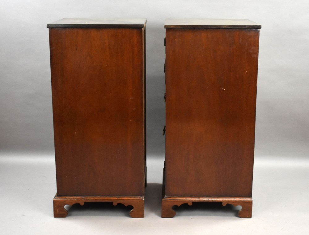 A matching pair of tall, narrow mahogany bedside chests, each featuring five drawers with brass handles and resting on bracket feet. View II