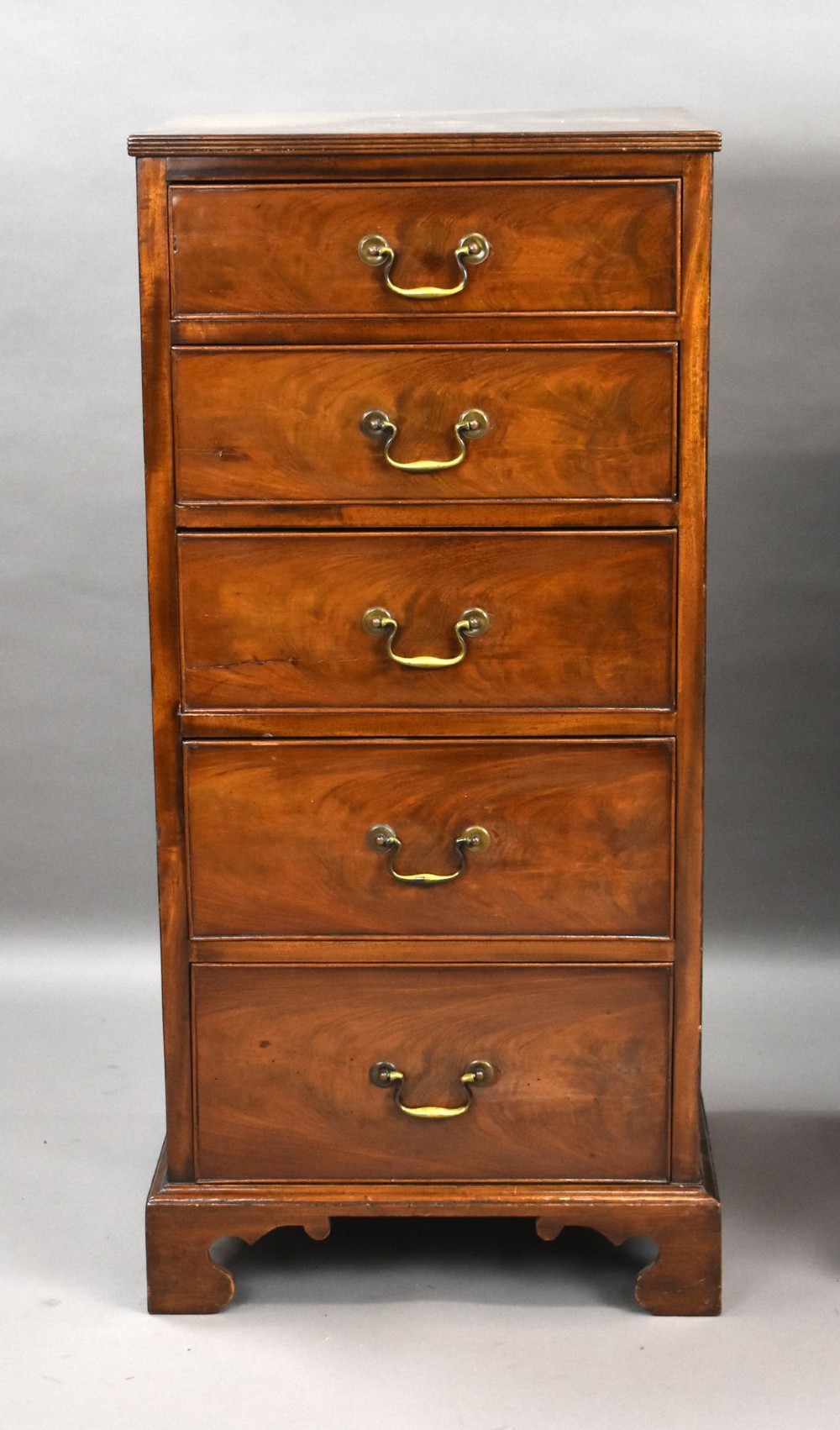 A matching pair of tall, narrow mahogany bedside chests, each featuring five drawers with brass handles and resting on bracket feet. View III