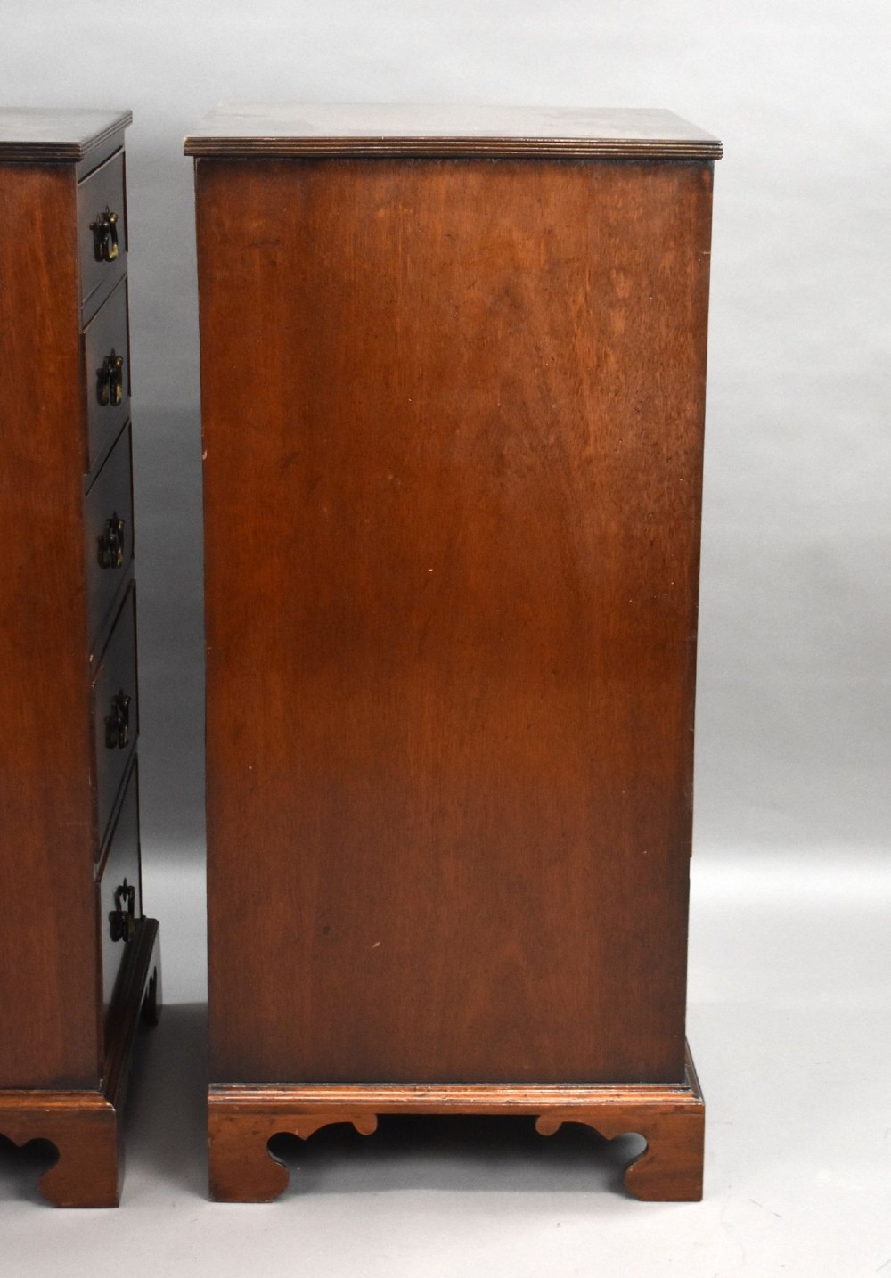 A matching pair of tall, narrow mahogany bedside chests, each featuring five drawers with brass handles and resting on bracket feet. View VII