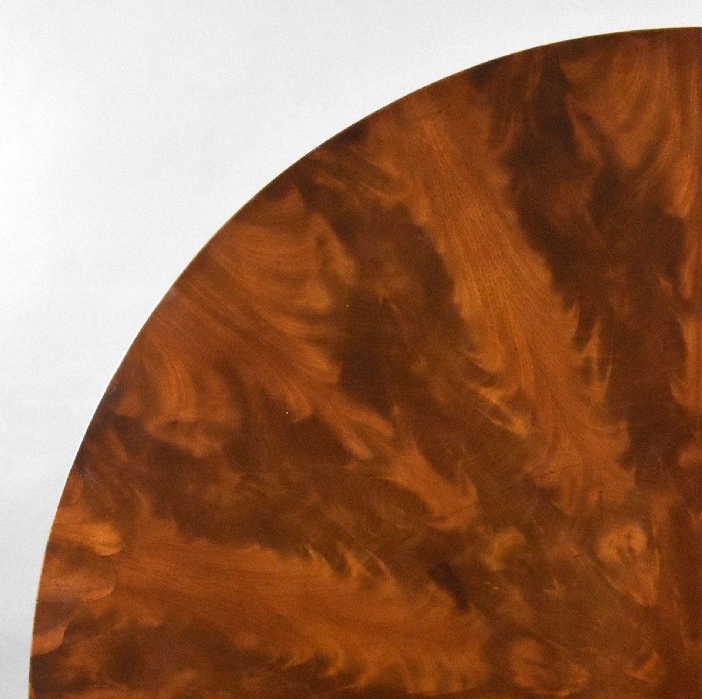 A circular Regency tilt-top breakfast table with starburst flame mahogany veneers shown tilted upright on a pedestal base. View IV
