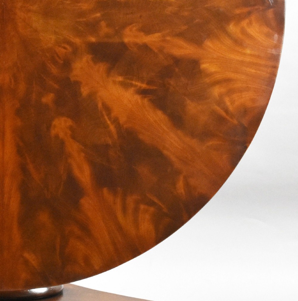 A circular Regency tilt-top breakfast table with starburst flame mahogany veneers shown tilted upright on a pedestal base. View VI