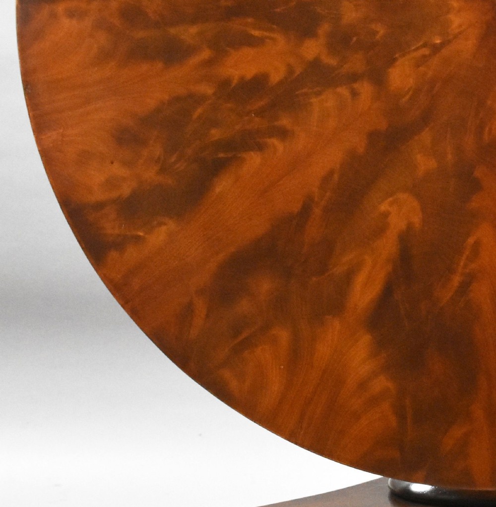 A circular Regency tilt-top breakfast table with starburst flame mahogany veneers shown tilted upright on a pedestal base. View VII