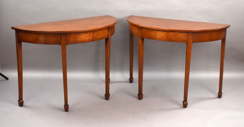 A pair of Georgian mahogany demilune console tables featuring semi-circular tops, plain aprons, and square tapered legs. View II