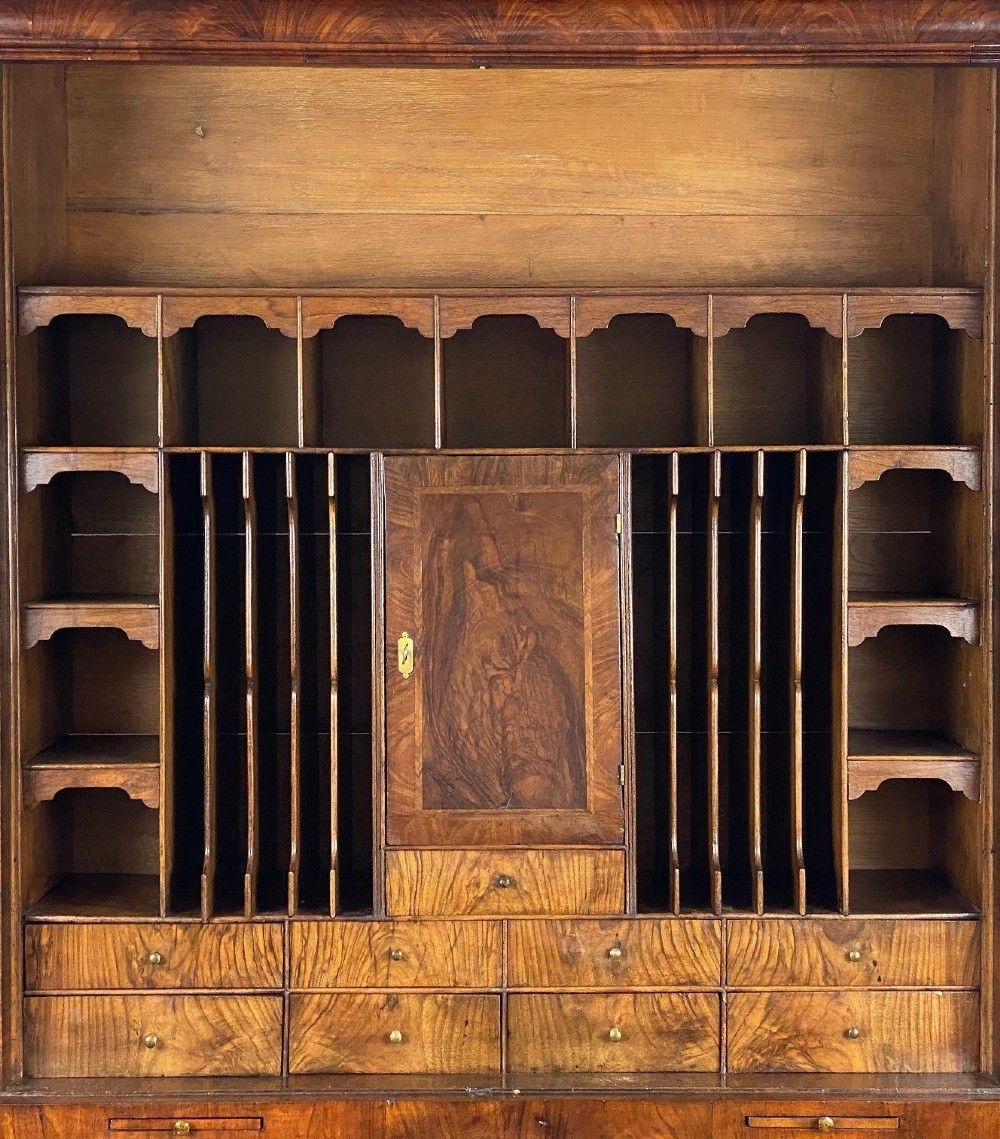 A George II burr walnut bureau bookcase featuring an upper double-door cabinet with shaped mirrored panels over a fall-front desk and four drawers with brass handles. View IV
