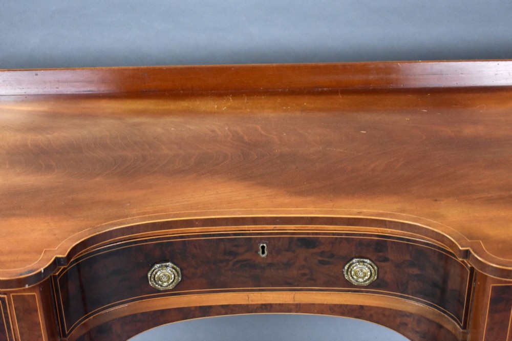 A George III mahogany sideboard featuring an inlaid concave centre, multiple drawers with circular brass handles, and square tapered legs with spade feet. View IX