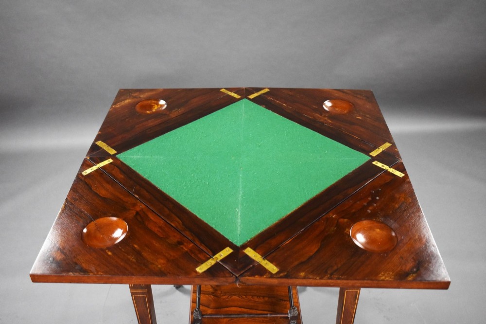 An Edwardian inlaid rosewood envelope card table with tapered square legs, brass castors, a lower undertier shelf, and a top split into four triangular leaves. View VII