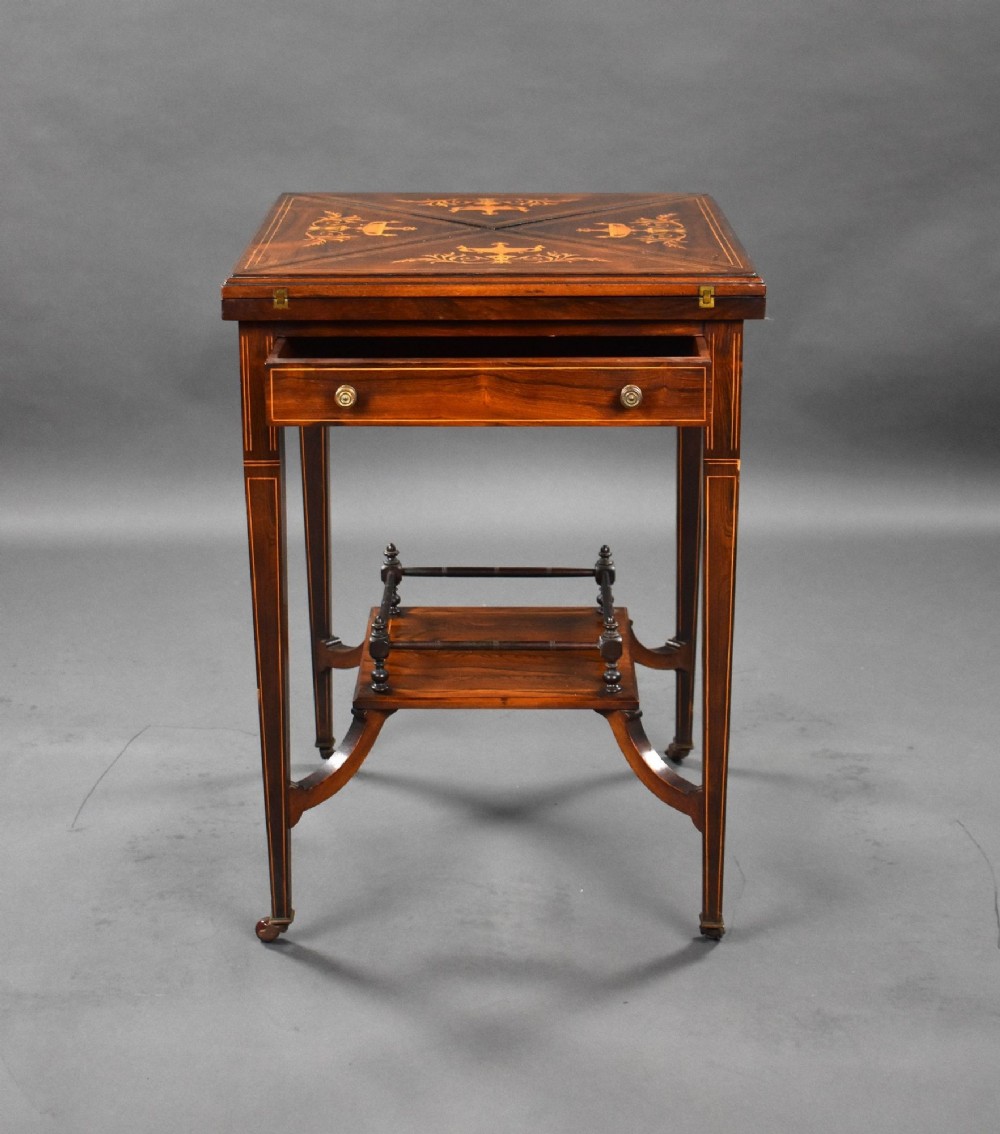An Edwardian inlaid rosewood envelope card table with tapered square legs, brass castors, a lower undertier shelf, and a top split into four triangular leaves. View XII
