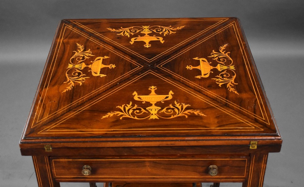 An Edwardian inlaid rosewood envelope card table with tapered square legs, brass castors, a lower undertier shelf, and a top split into four triangular leaves. View XIV