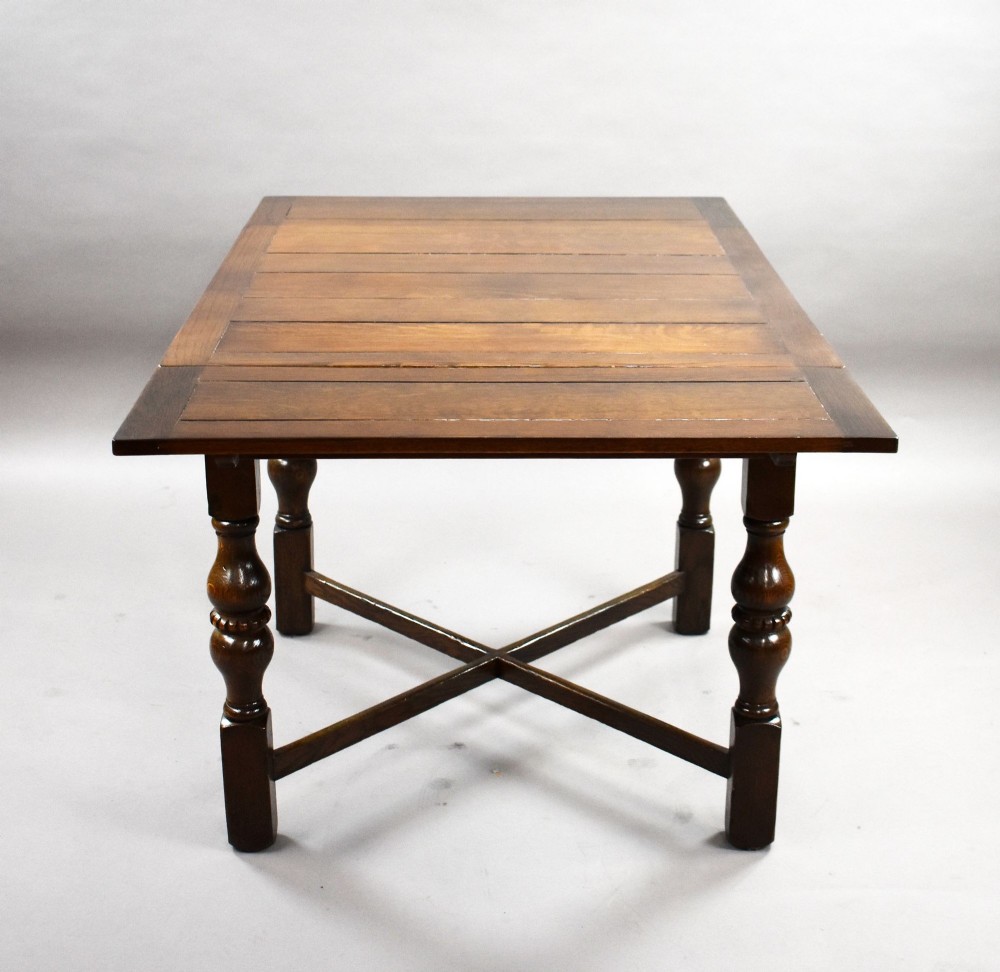 An antique warm brown oak draw-leaf dining table surrounded by four matching carved wooden chairs with light upholstery. View III