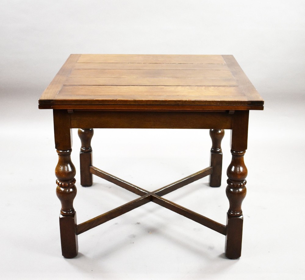 An antique warm brown oak draw-leaf dining table surrounded by four matching carved wooden chairs with light upholstery. View IV