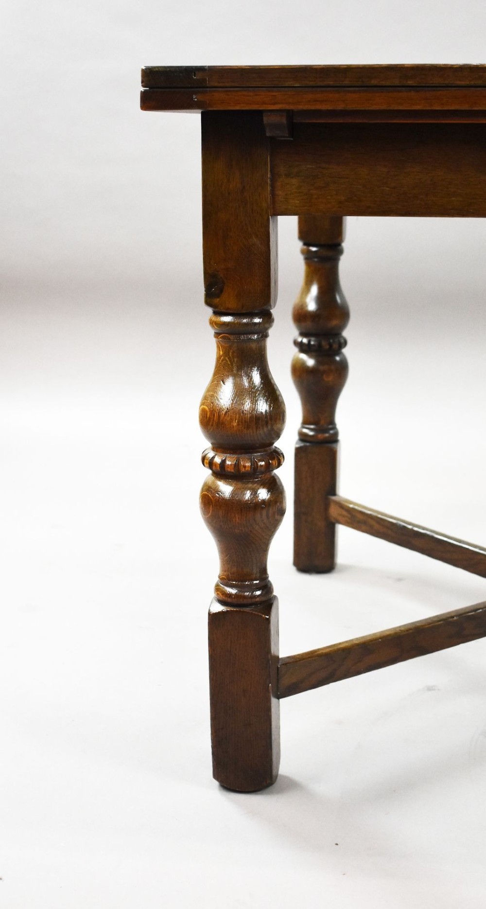 An antique warm brown oak draw-leaf dining table surrounded by four matching carved wooden chairs with light upholstery. View V