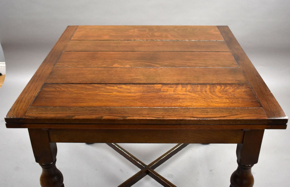 An antique warm brown oak draw-leaf dining table surrounded by four matching carved wooden chairs with light upholstery. View VI