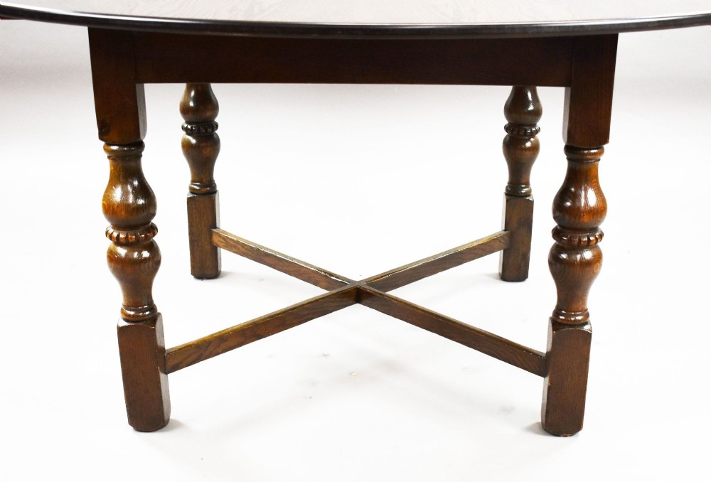 An antique warm brown oak draw-leaf dining table surrounded by four matching carved wooden chairs with light upholstery. View VIII