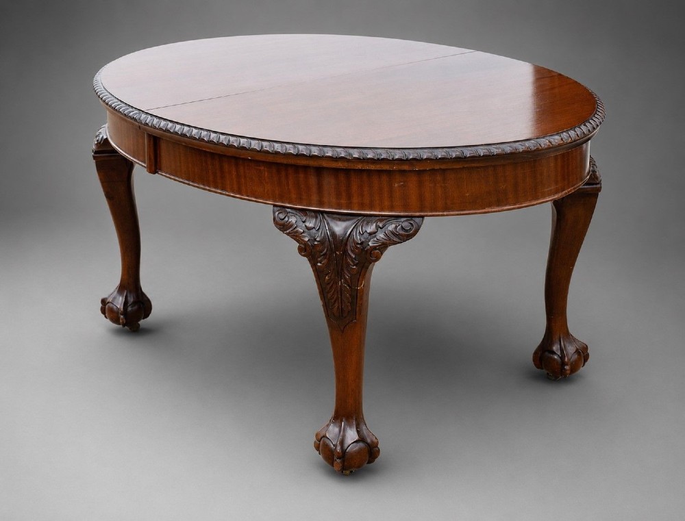 An Edwardian mahogany extending dining table surrounded by matching Chippendale style dining chairs with striped upholstered seats and carved ball and claw feet. View IV