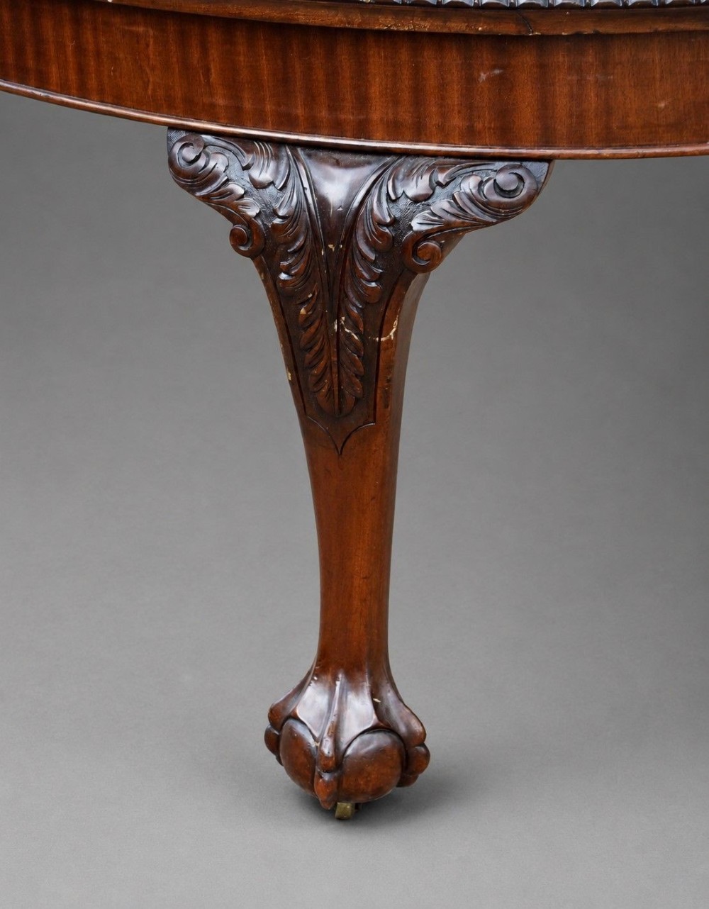 An Edwardian mahogany extending dining table surrounded by matching Chippendale style dining chairs with striped upholstered seats and carved ball and claw feet. View V