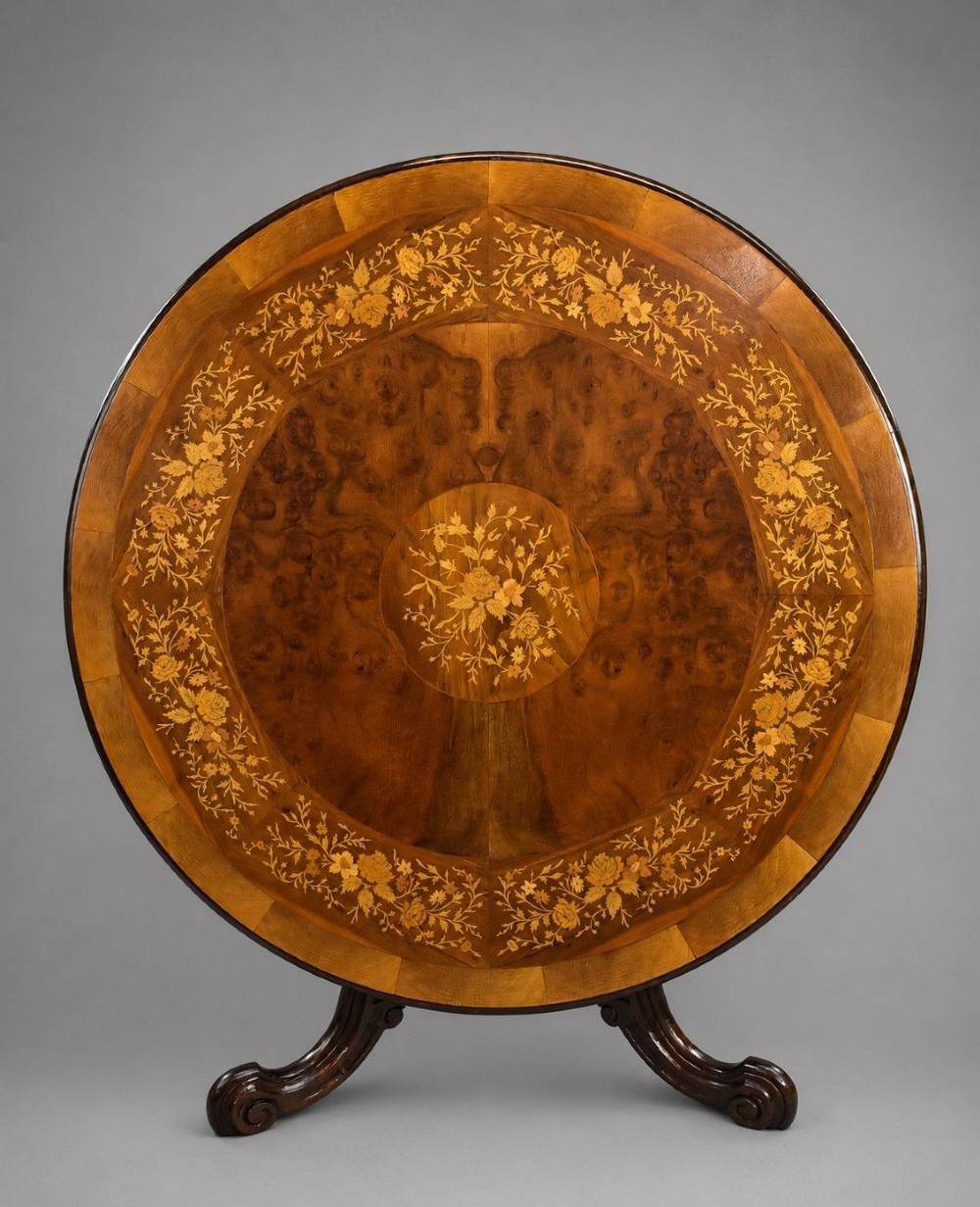 A Victorian circular burr walnut centre table featuring floral marquetry inlays on the tabletop and a dark carved pedestal base.