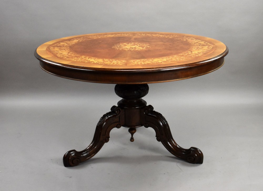 A Victorian circular burr walnut centre table featuring floral marquetry inlays on the tabletop and a dark carved pedestal base. View II