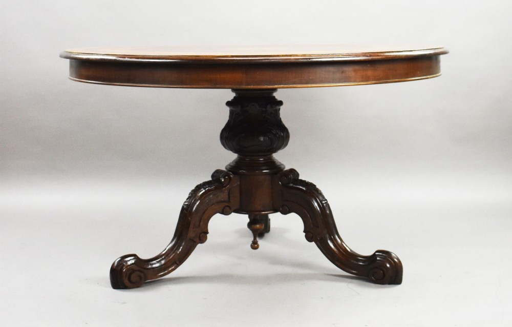 A Victorian circular burr walnut centre table featuring floral marquetry inlays on the tabletop and a dark carved pedestal base. View III
