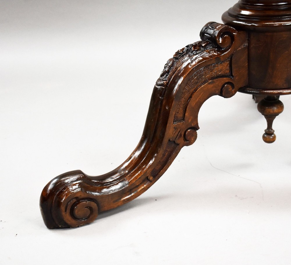 A Victorian circular burr walnut centre table featuring floral marquetry inlays on the tabletop and a dark carved pedestal base. View VII