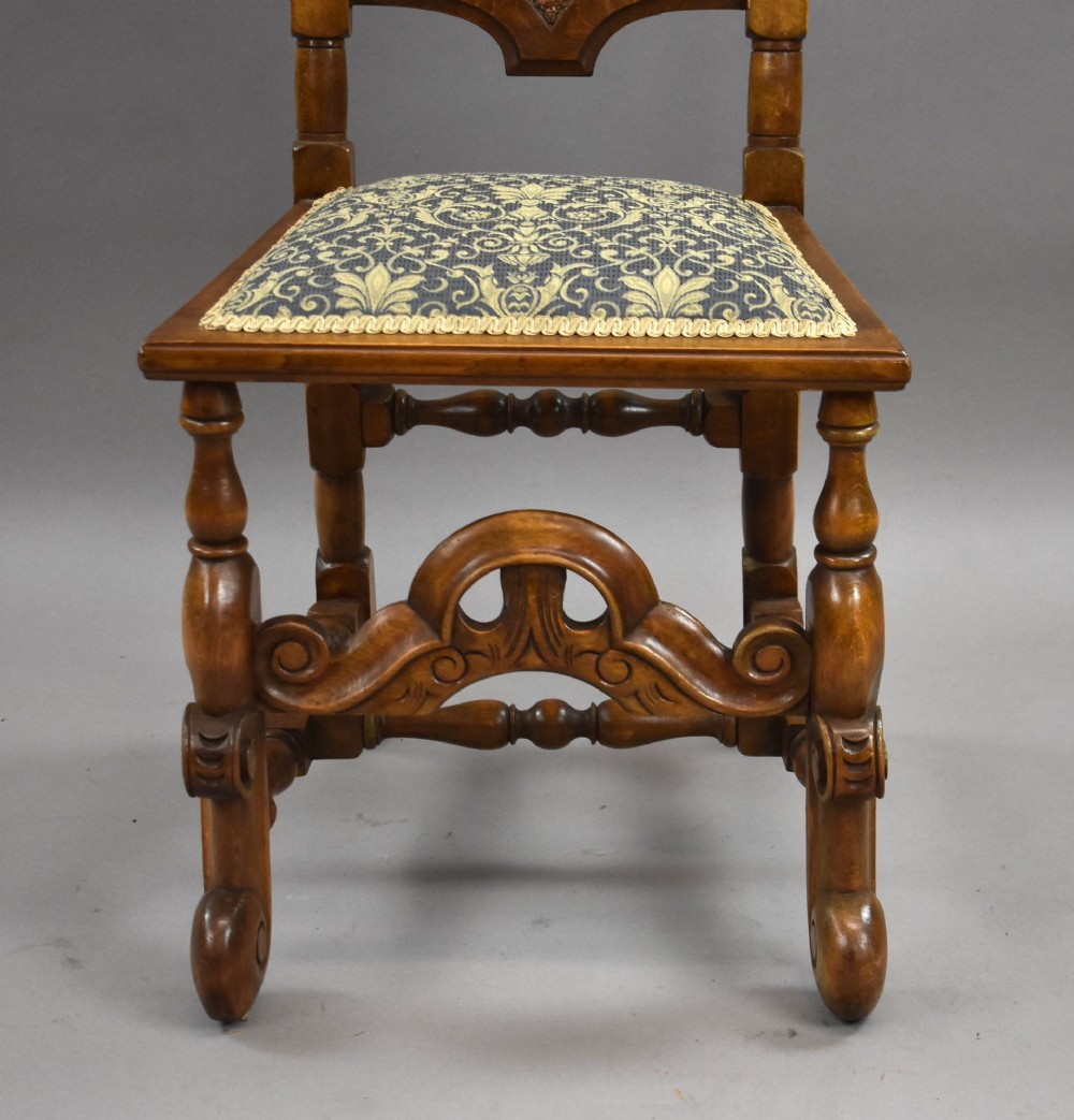 A long dark oak refectory style dining table surrounded by ten high-back carved oak chairs with woven cane back panels and patterned upholstered seats. View VI