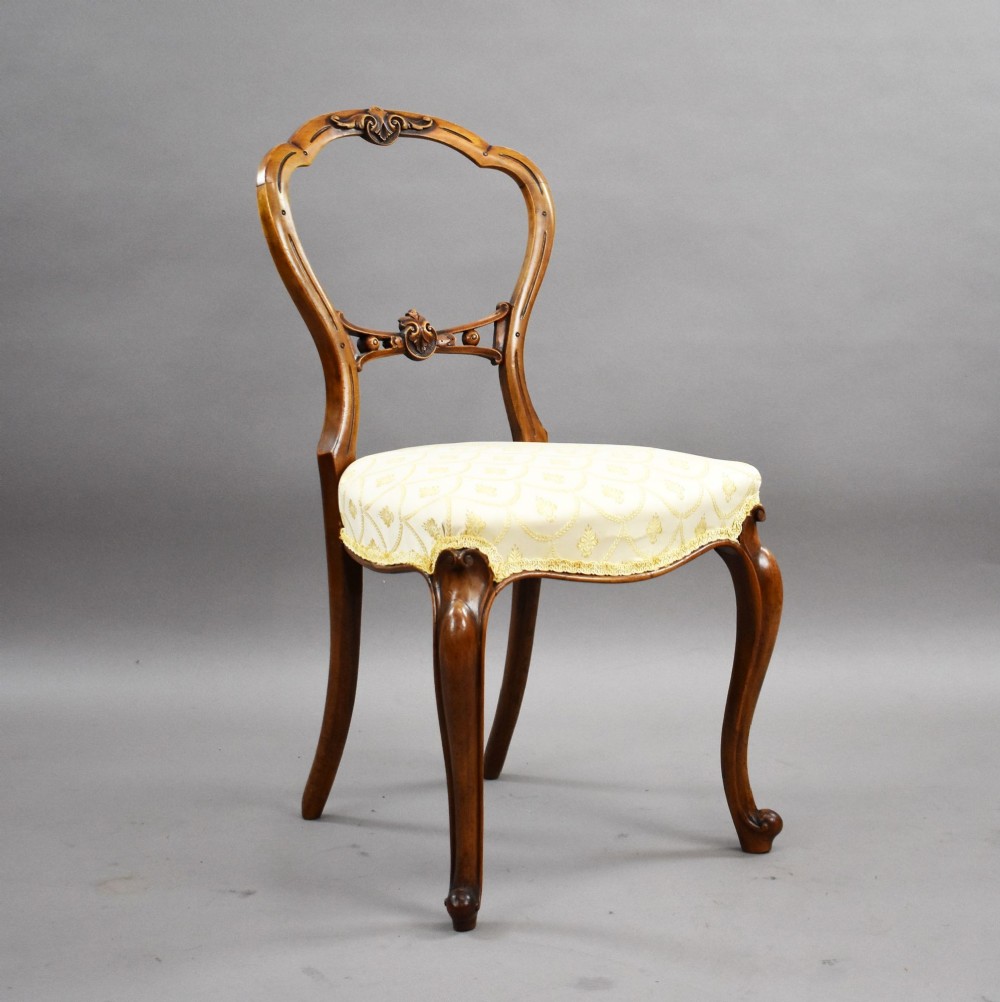 A set of four Victorian walnut balloon back dining chairs with carved horizontal splats, cabriole front legs, and cream pattern upholstered seats. View II