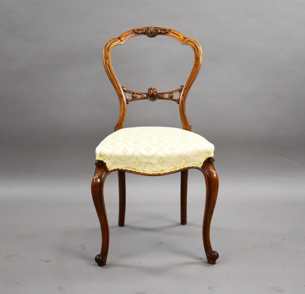 A set of four Victorian walnut balloon back dining chairs with carved horizontal splats, cabriole front legs, and cream pattern upholstered seats. View III