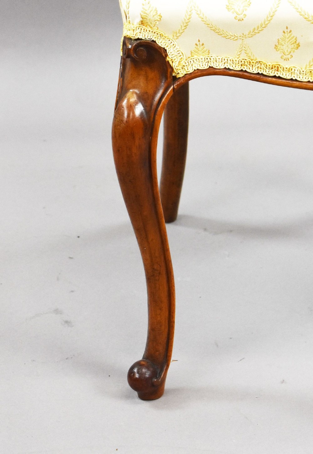 A set of four Victorian walnut balloon back dining chairs with carved horizontal splats, cabriole front legs, and cream pattern upholstered seats. View V
