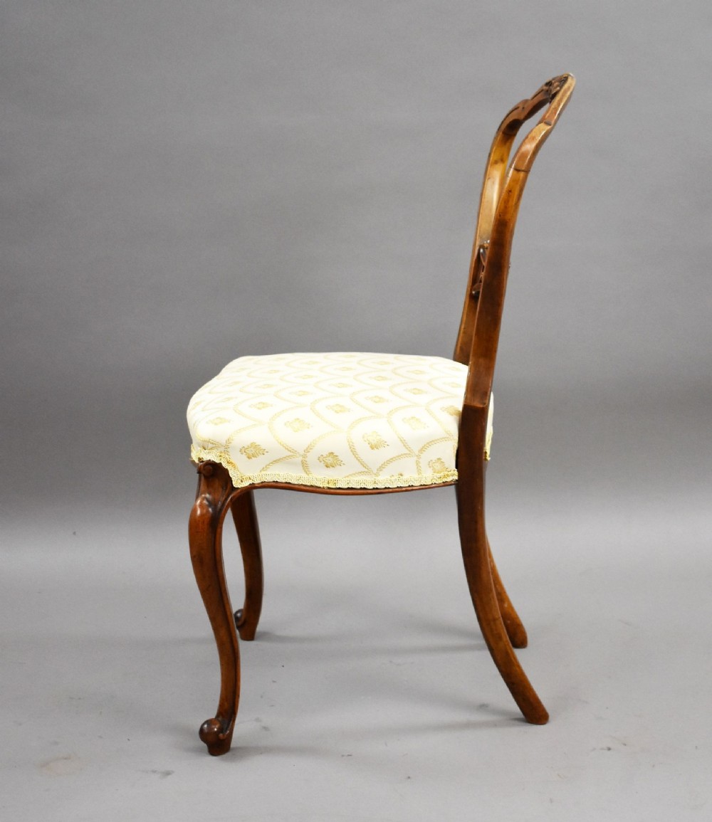 A set of four Victorian walnut balloon back dining chairs with carved horizontal splats, cabriole front legs, and cream pattern upholstered seats. View VIII