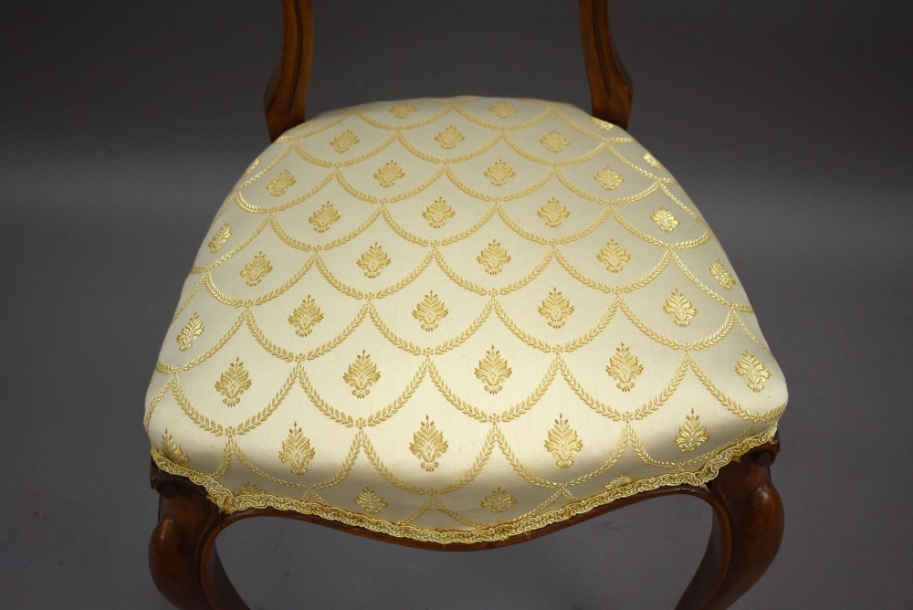 A set of four Victorian walnut balloon back dining chairs with carved horizontal splats, cabriole front legs, and cream pattern upholstered seats. View IX