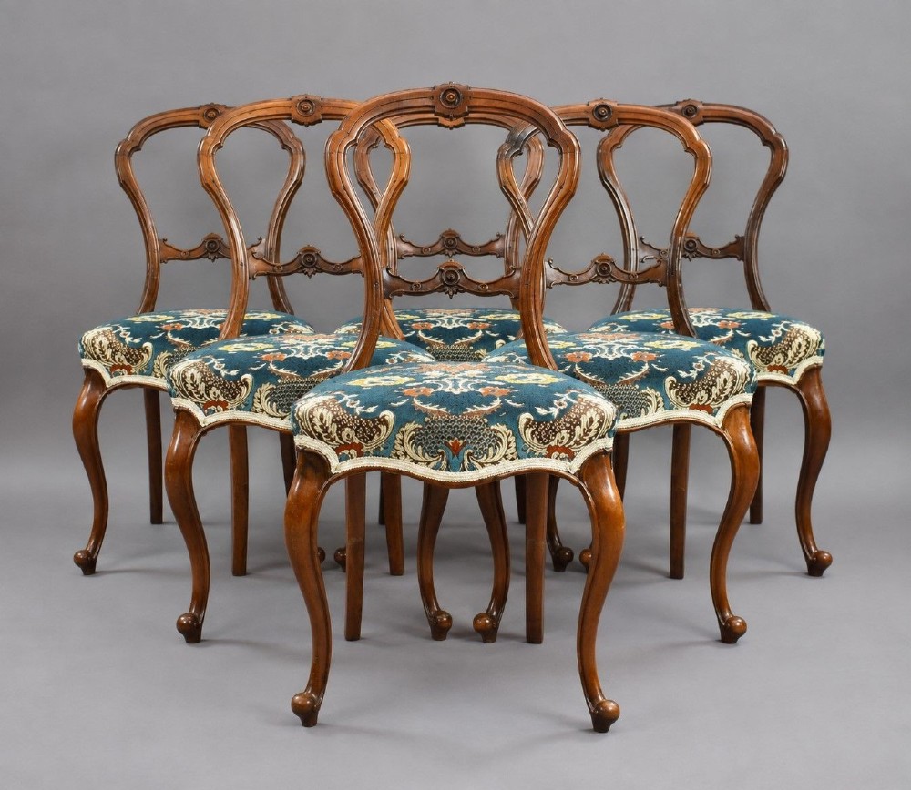 A set of six Victorian mahogany dining chairs featuring carved balloon backrests, blue patterned upholstery, and elegant cabriole legs.