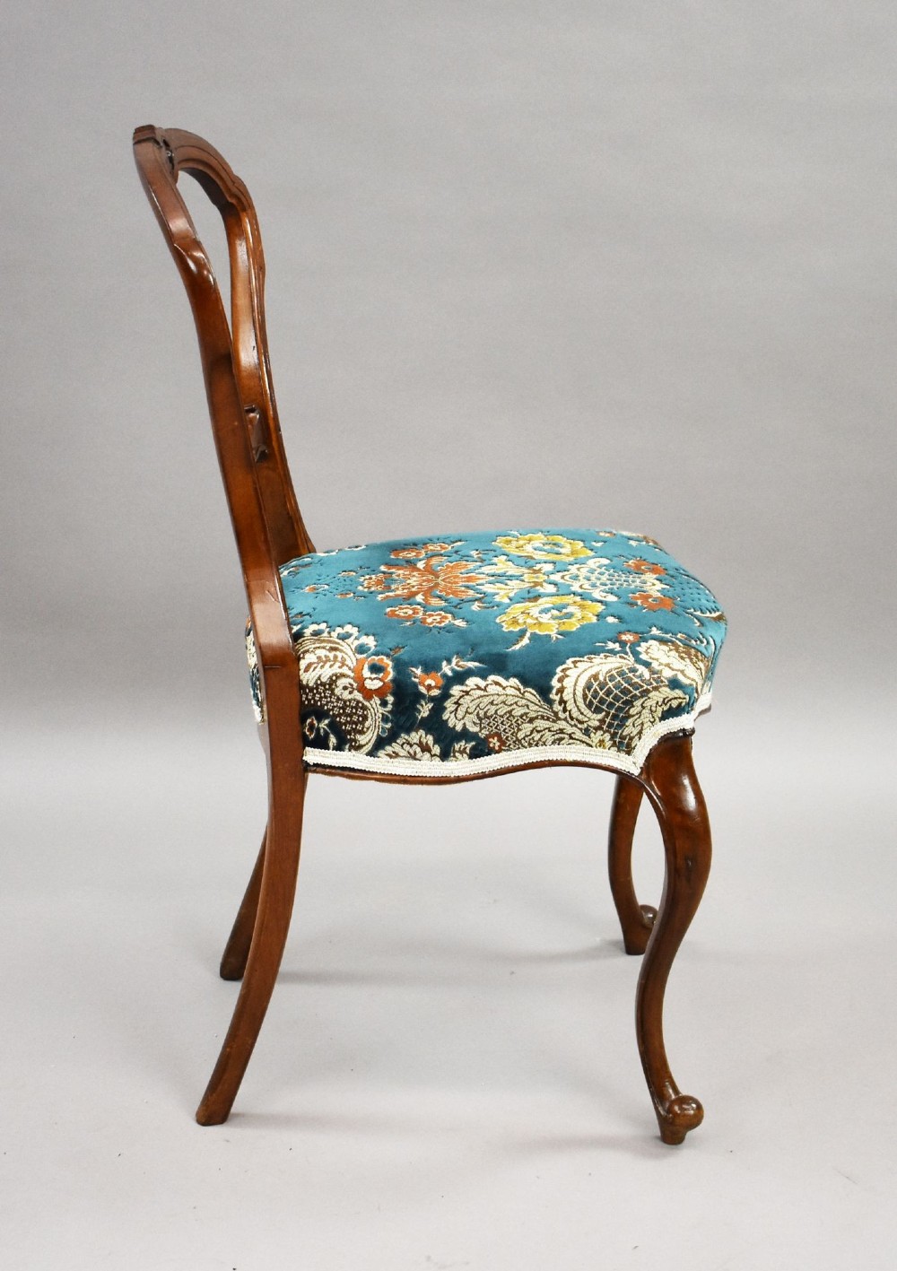 A set of six Victorian mahogany dining chairs featuring carved balloon backrests, blue patterned upholstery, and elegant cabriole legs. View V