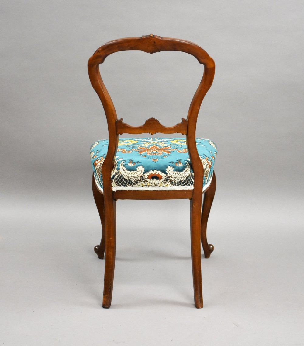 A set of six Victorian mahogany dining chairs featuring carved balloon backrests, blue patterned upholstery, and elegant cabriole legs. View VI