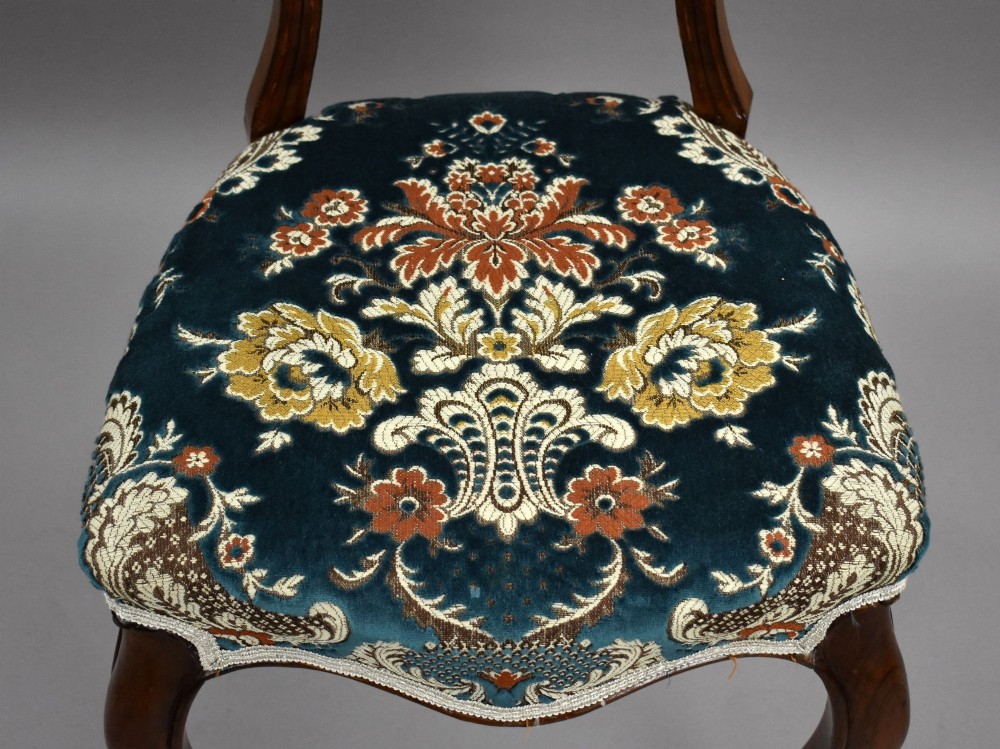 A set of six Victorian mahogany dining chairs featuring carved balloon backrests, blue patterned upholstery, and elegant cabriole legs. View IX