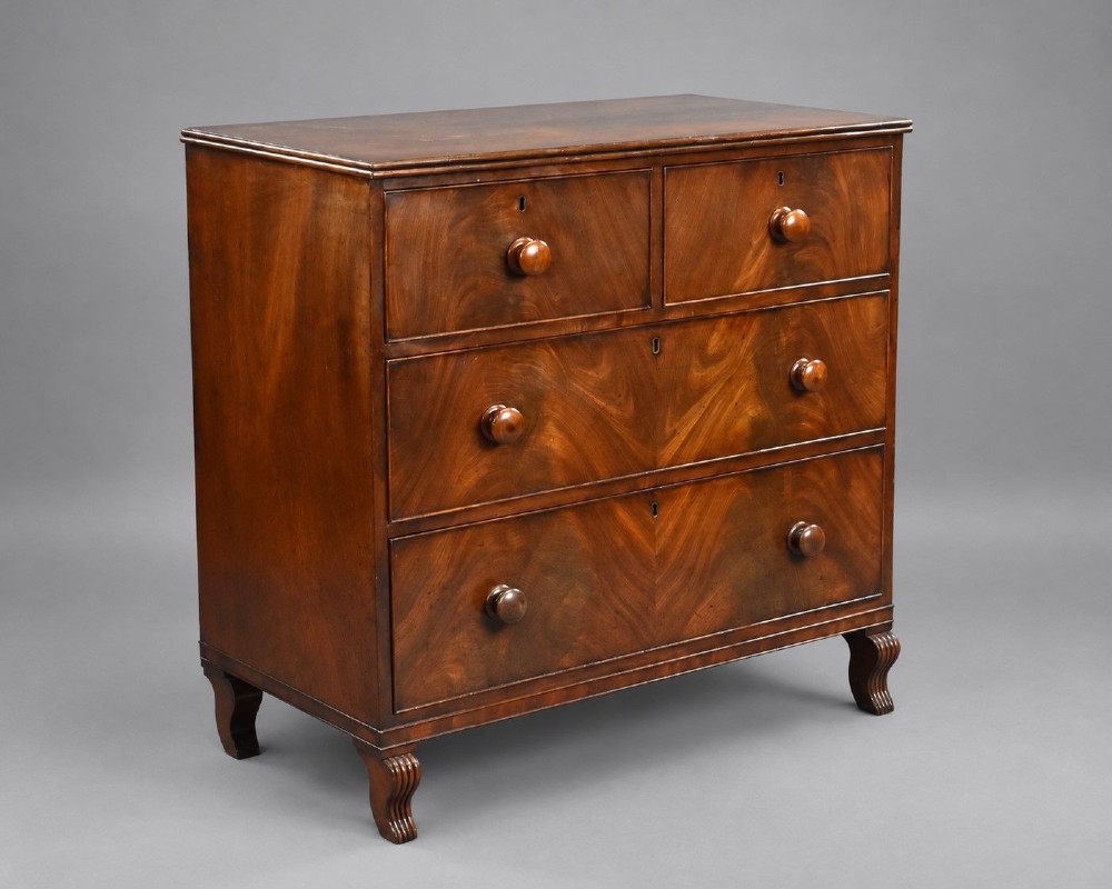 A Regency flame mahogany chest of drawers featuring two short over two long drawers with turned timber knobs and shaped bracket feet.