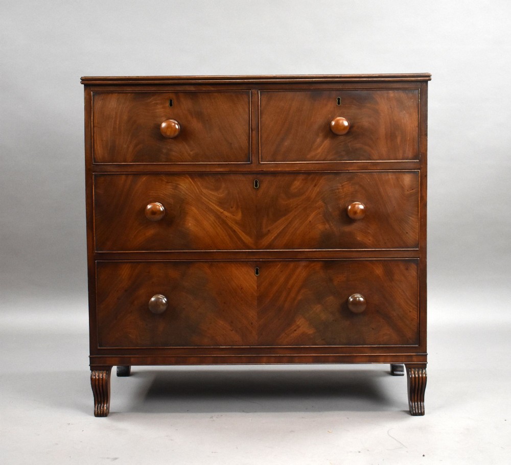 A Regency flame mahogany chest of drawers featuring two short over two long drawers with turned timber knobs and shaped bracket feet. View II