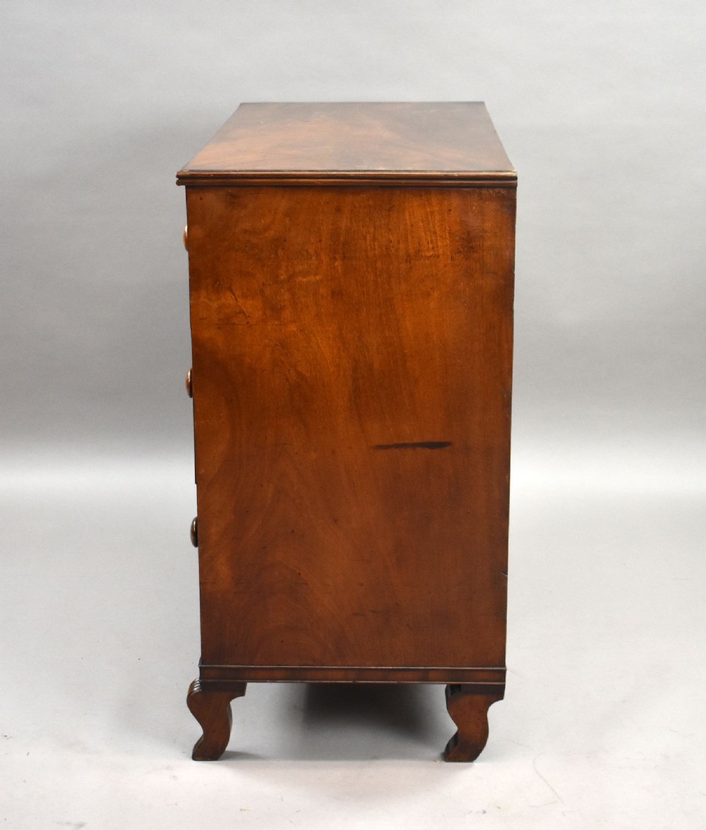 A Regency flame mahogany chest of drawers featuring two short over two long drawers with turned timber knobs and shaped bracket feet. View IV