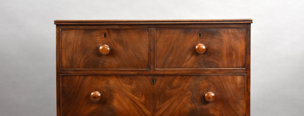 A Regency flame mahogany chest of drawers featuring two short over two long drawers with turned timber knobs and shaped bracket feet. View VI