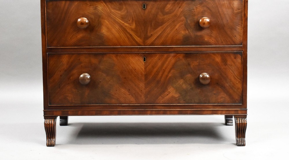 A Regency flame mahogany chest of drawers featuring two short over two long drawers with turned timber knobs and shaped bracket feet. View VII