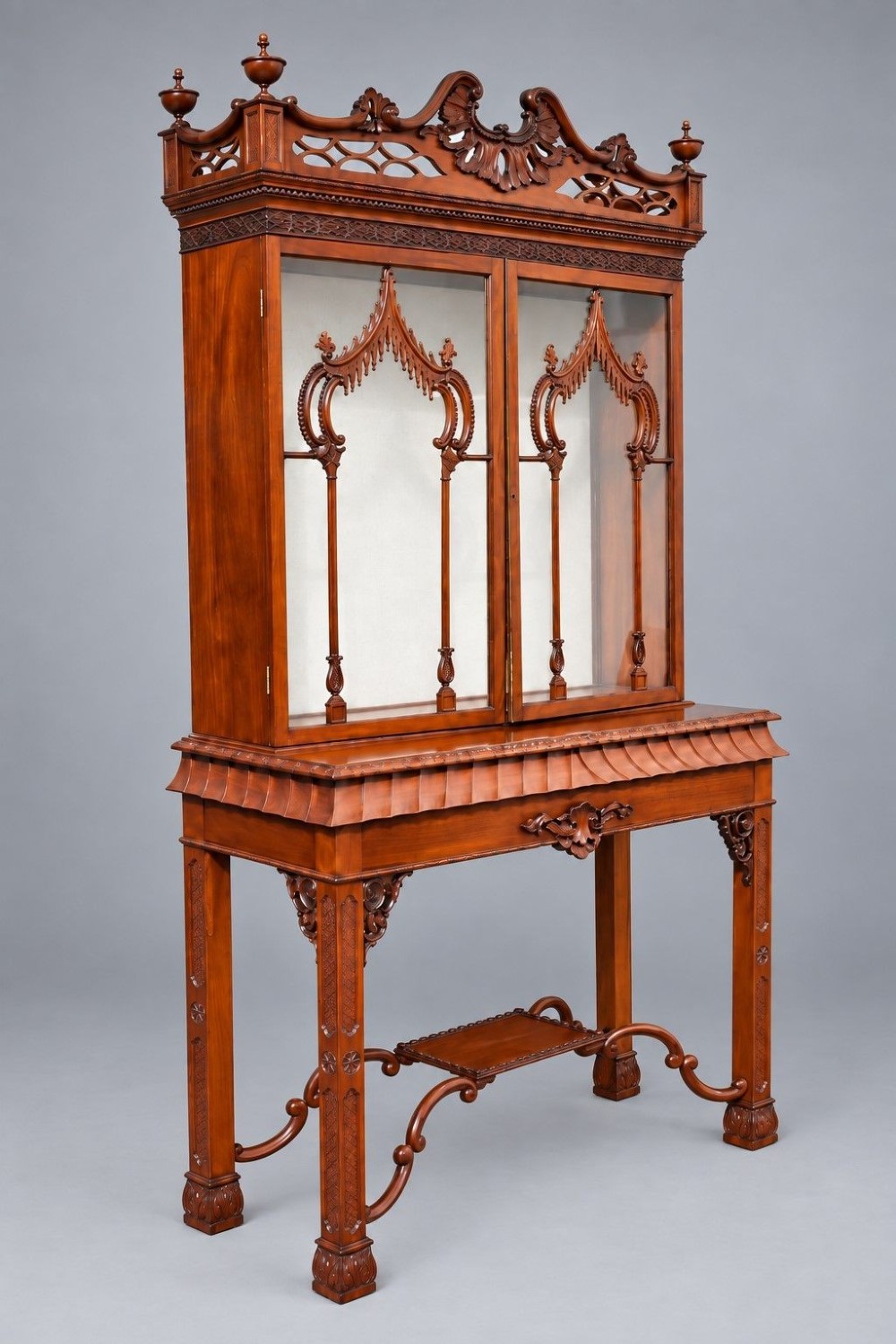 A late Victorian mahogany display cabinet in the Chinese Chippendale style with a pierced cresting, glazed tracery doors, and carved legs with an under-tier.
