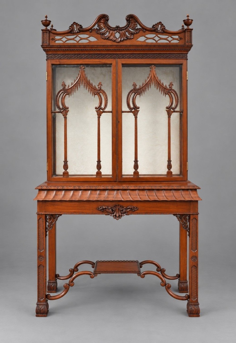 A late Victorian mahogany display cabinet in the Chinese Chippendale style with a pierced cresting, glazed tracery doors, and carved legs with an under-tier. View II